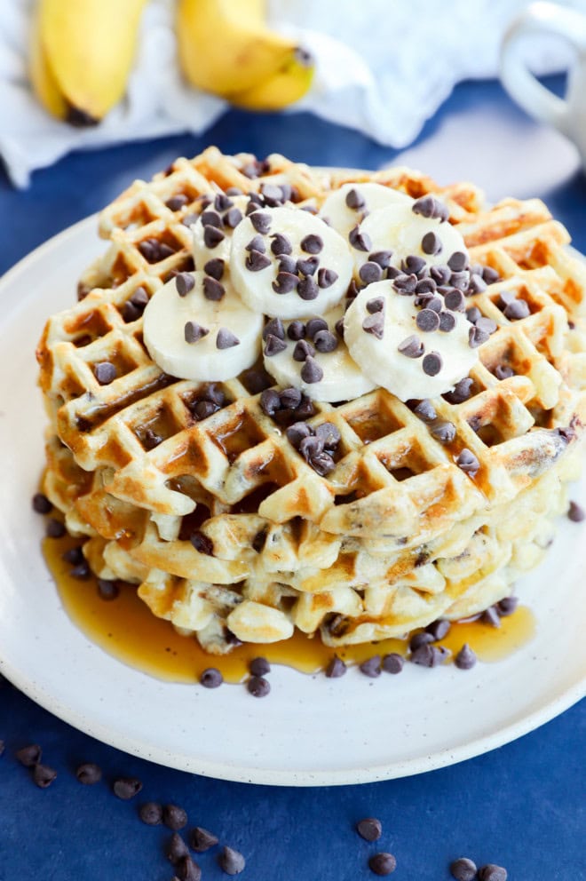 syrup on banana waffles stack on plate with fresh bananas in background