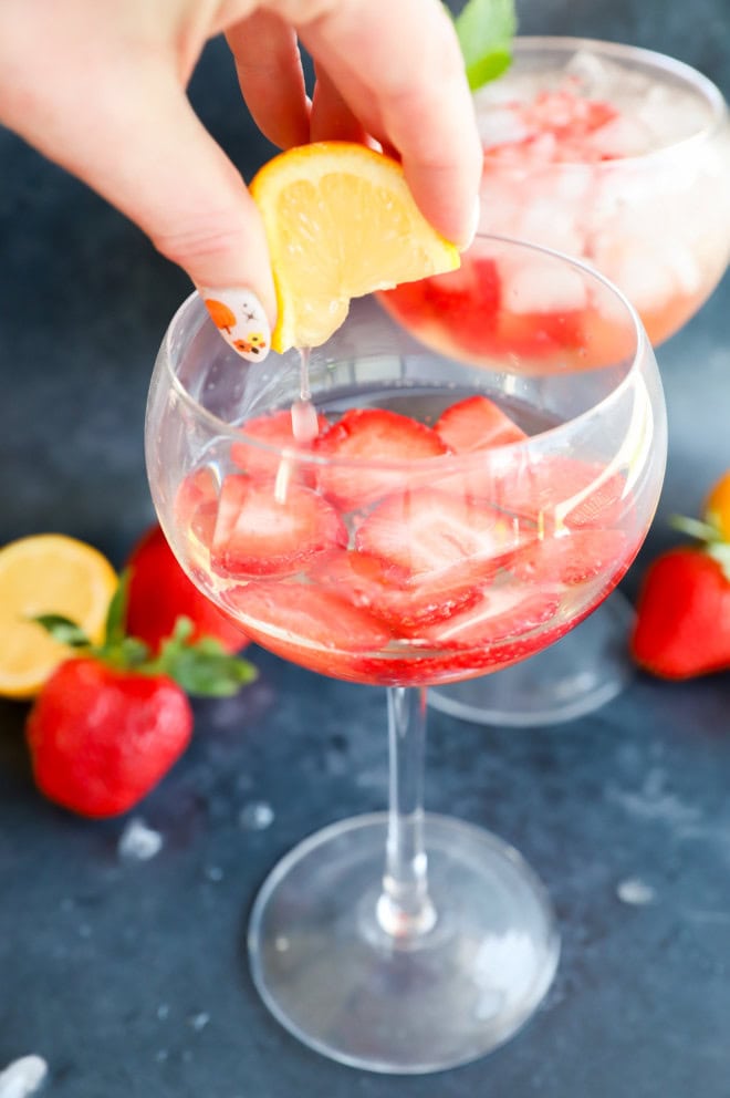 Squeezing a lemon into a glass with fresh berries