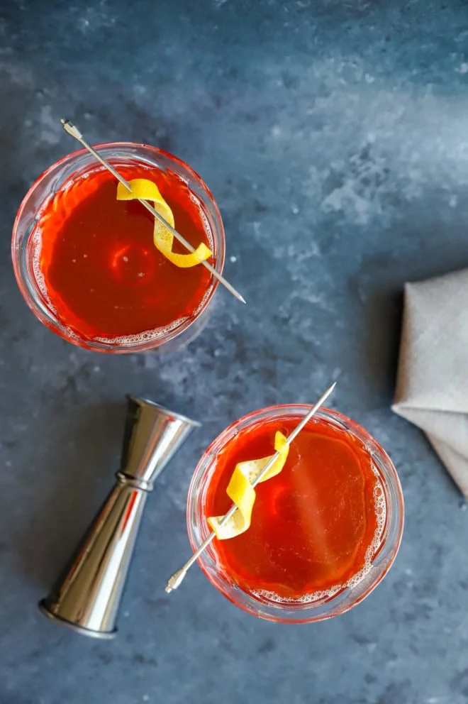 overhead image of coupe glasses with paper plane cocktails and jigger