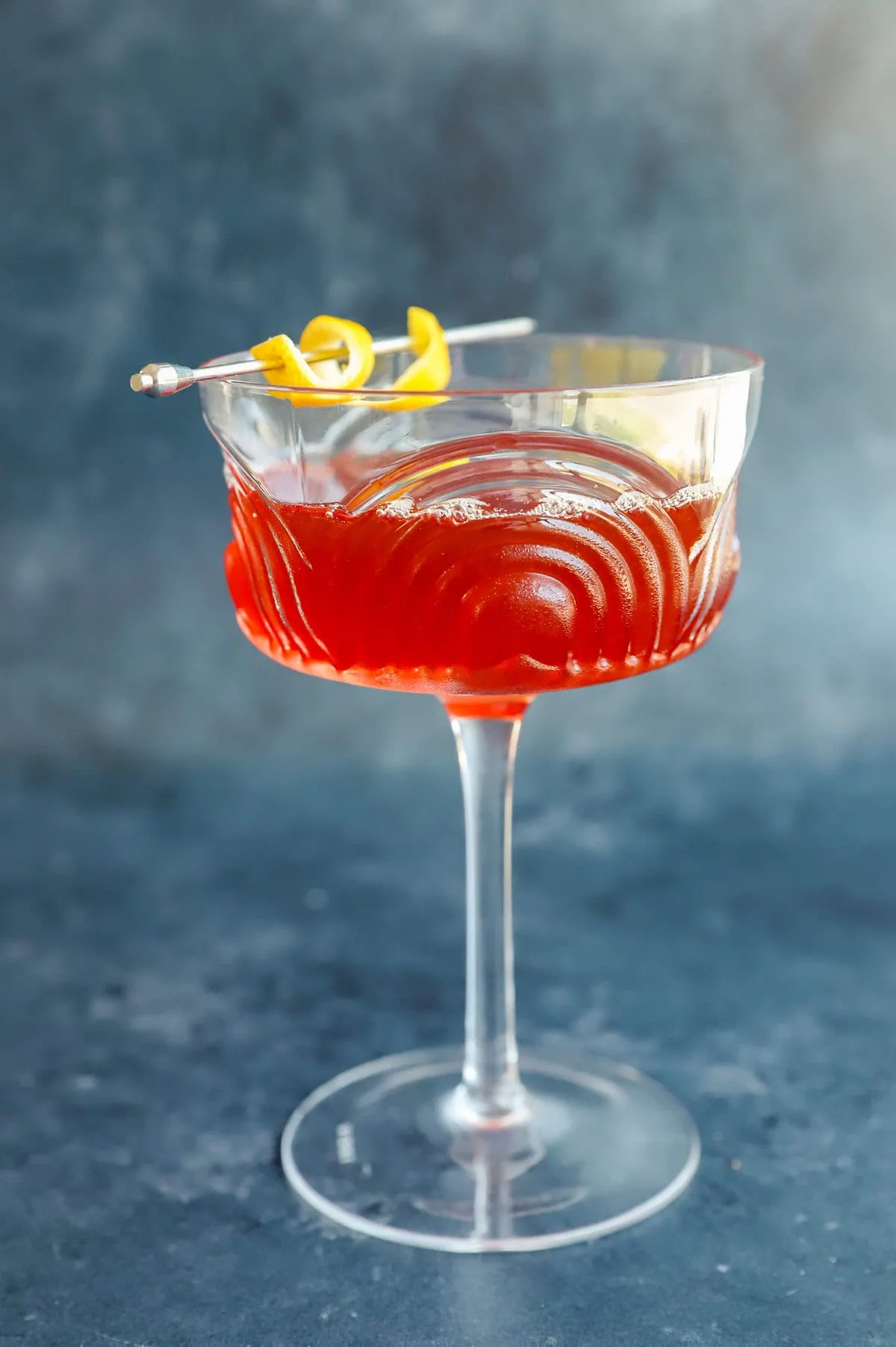 easy aperol bourbon cocktail in coupe glass with lemon peel garnish