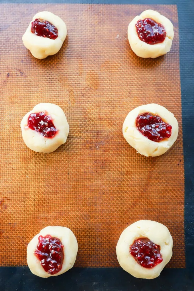 raspberry thumbprint cookies on a baking pan before baking