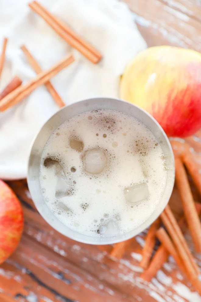 making an apple cider cocktail in a shaker filled with ice