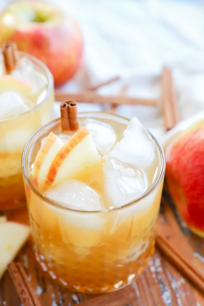 apple cider cocktail in cocktail glass with apple slices and cinnamon stick