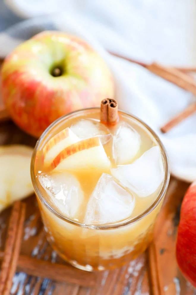 easy apple cider cocktail in glass with fresh apples and cinnamon sticks