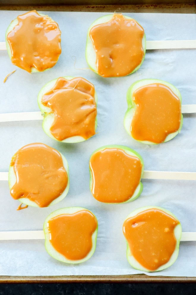 caramel on top of apple slices with popsicle sticks