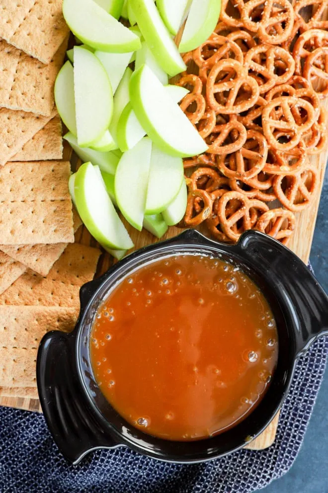 caramel apple dip in a bat bowl on platter with pretzels, graham crackers, and apple slices