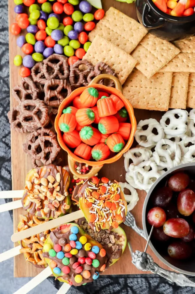 halloween dessert charcuterie board with candy apple slices, candies, and pretzels