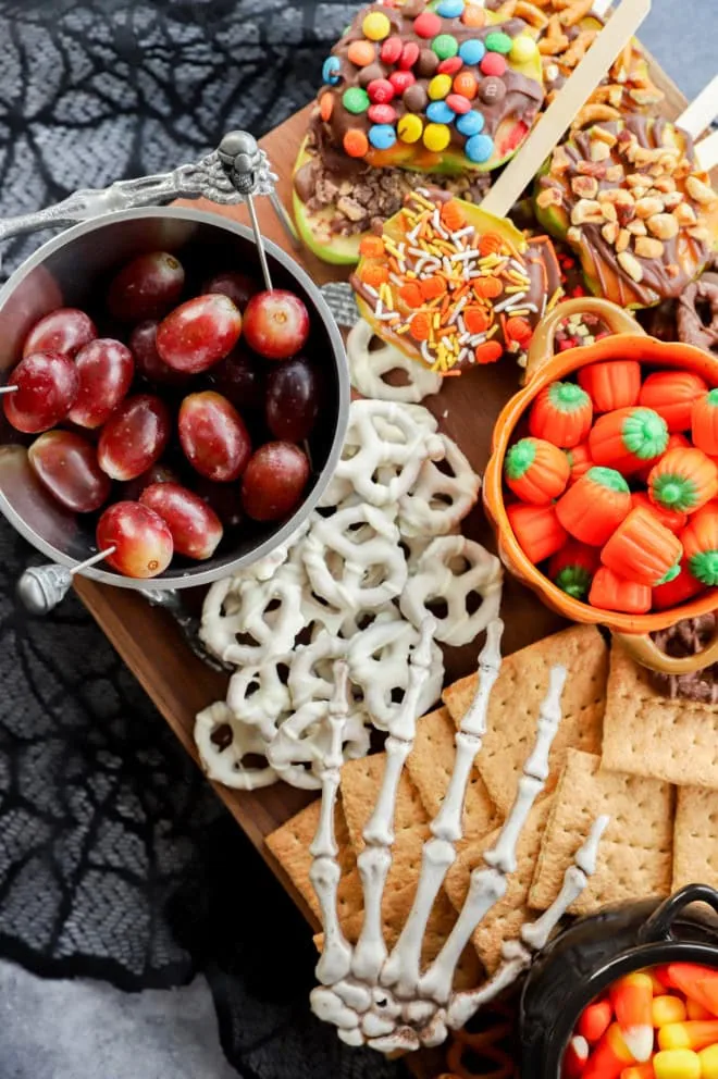 skeleton hand reaching for graham crackers on a halloween dessert charcuterie board