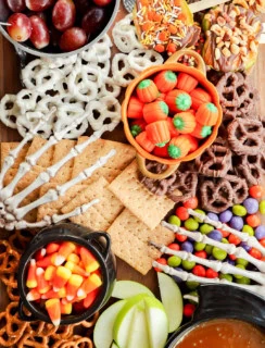 skeleton hands on a sweet treat platter with candies, fruits, and crackers