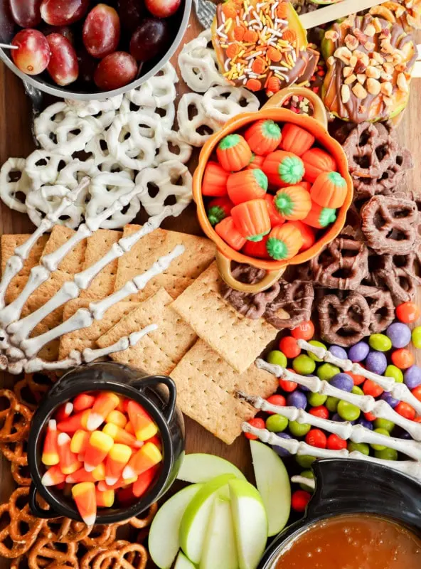 skeleton hands on a sweet treat platter with candies, fruits, and crackers