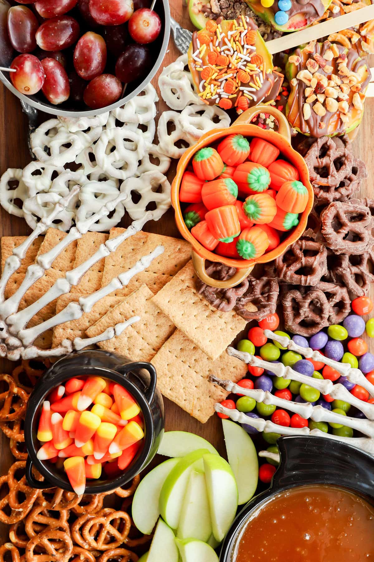 skeleton hands on a sweet treat platter with candies, fruits, and crackers