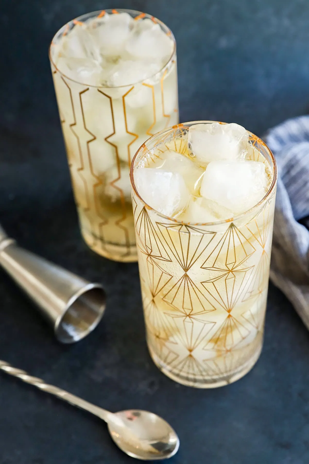 Cocktails in glasses with ice and whisky with spoon and jigger