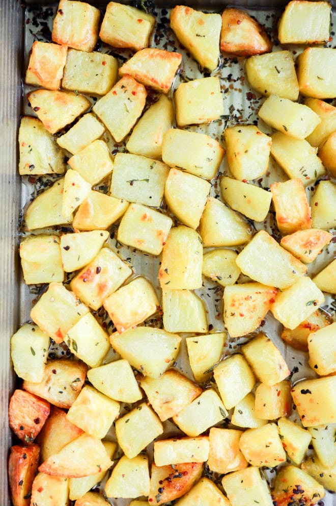 roasted root vegetables in a pan with fresh herbs