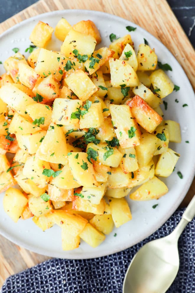 parmentier potatoes on a plate with gold spoon, wood, and black linen