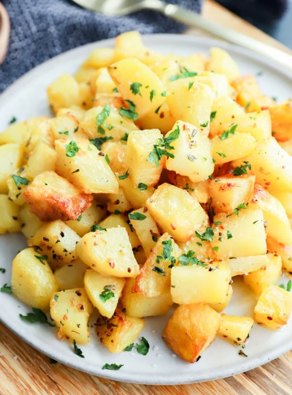 platter of golden potato cubes on platter with gold spoon