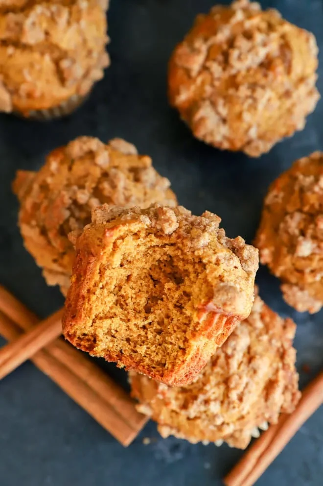 bite taken out of a pumpkin banana muffin on other muffins with cinnamon sticks