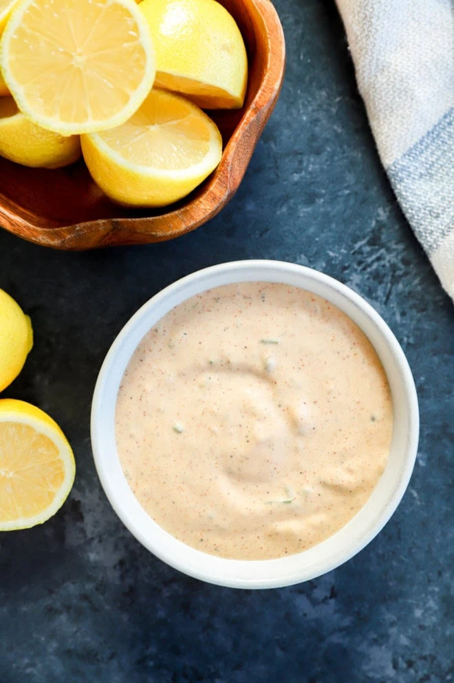 easy homemade remoulade sauce in bowl with bowl of lemons and blue linen