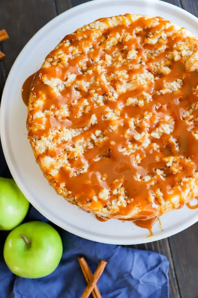 image of fall cake with caramel sauce on top fresh apples and cinnamon sticks