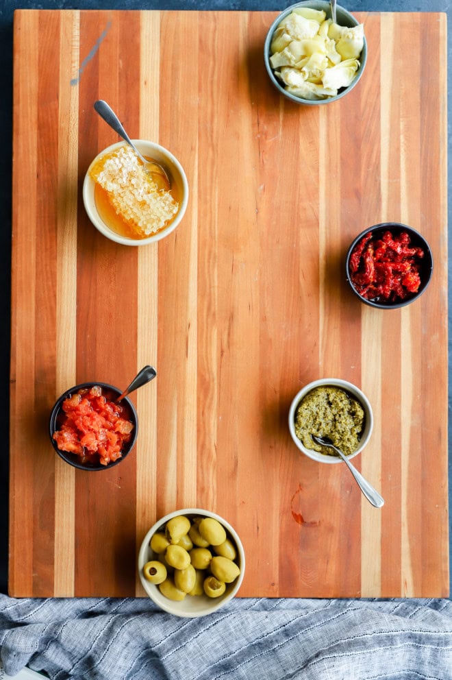 bowls on cutting board platter for italian charcuterie board assembly