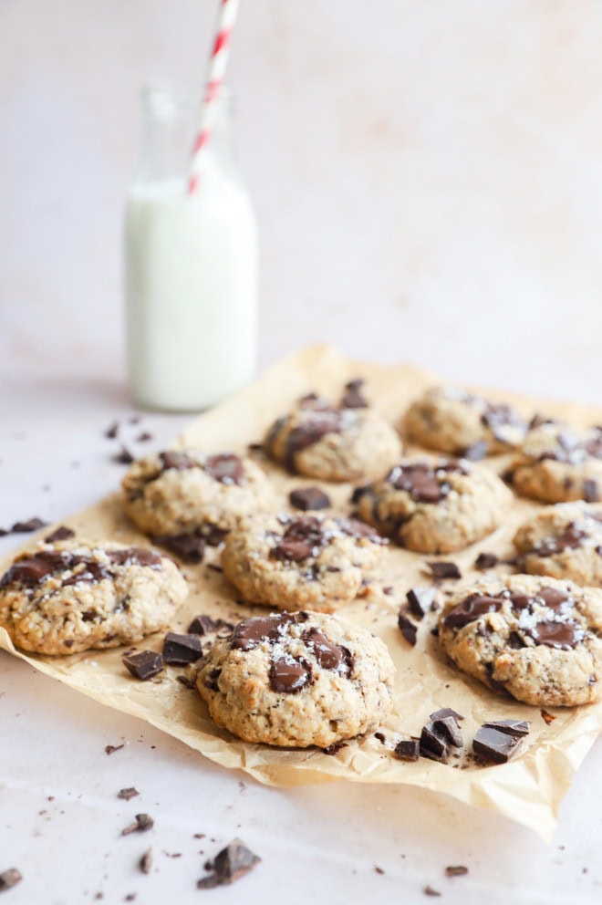 oatmeal chocolate chunk cookies on parchment paper with milk and a straw