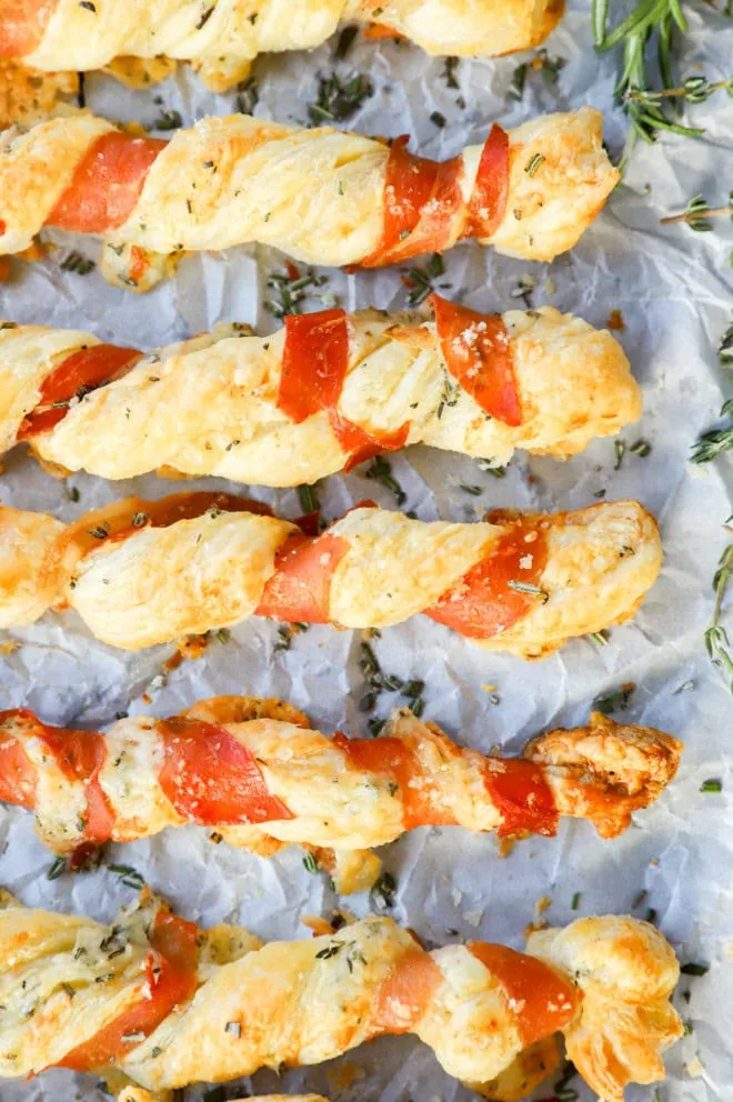 lined up puff pastry appetizers with cured meat and fresh herbs