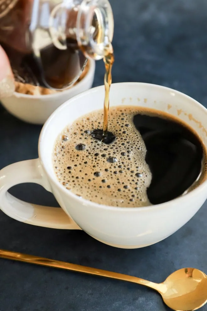 pouring brown sugar simple syrup into coffee