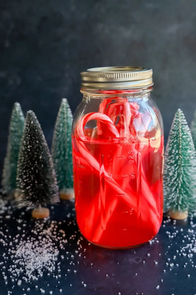 peppermint vodka with candy canes in a mason jar with christmas trees