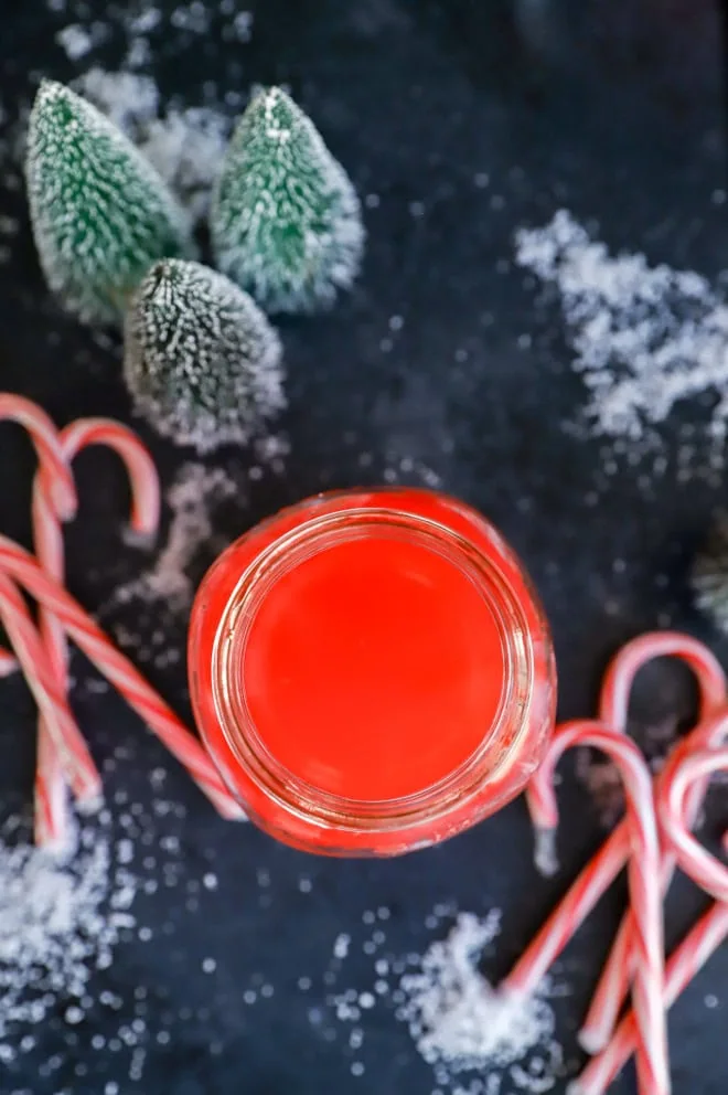 a bottle of peppermint vodka surrounded by trees and candy canes