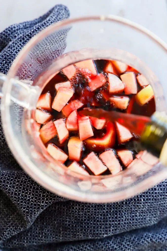 pouring spanish red wine into a red sangria pitcher