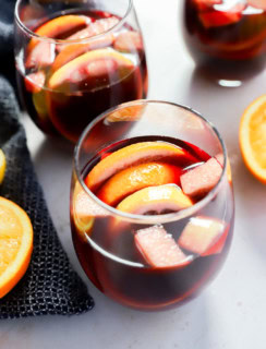 glasses of fruity punch with orange halves and a napkin