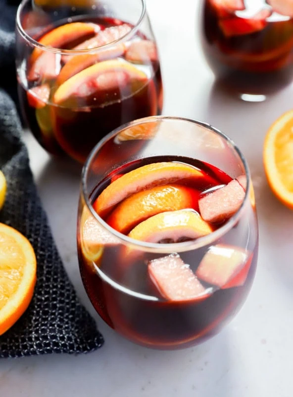 glasses of fruity punch with orange halves and a napkin