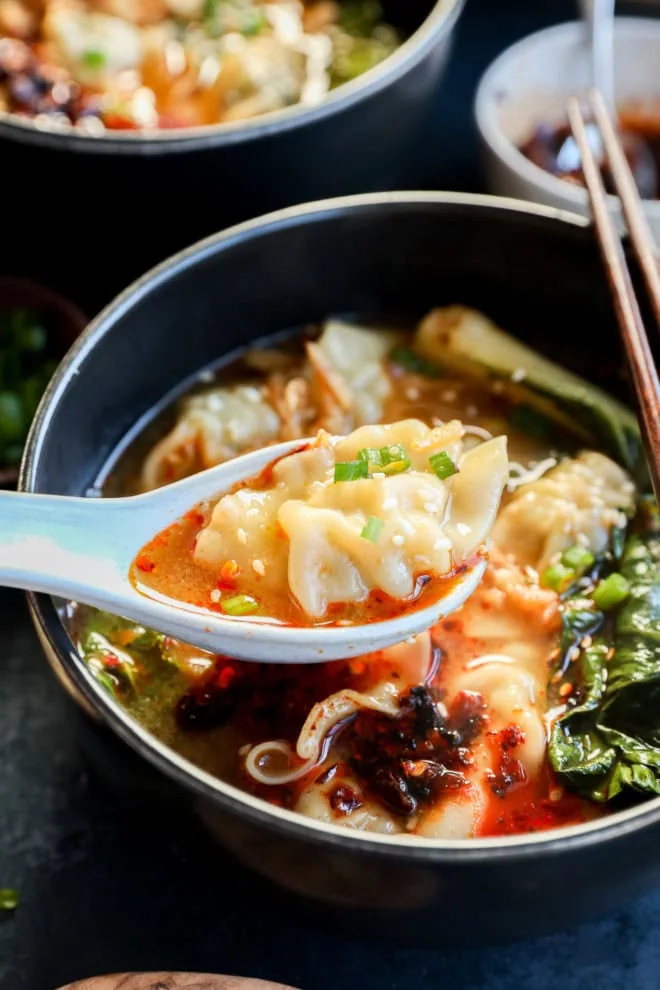 spooning out a dumpling with broth and bok choy