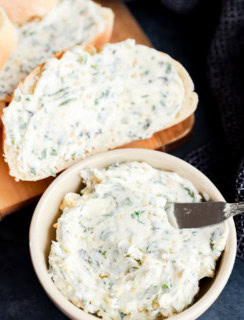 garlic herb butter in bowl and spread on bread on cutting board