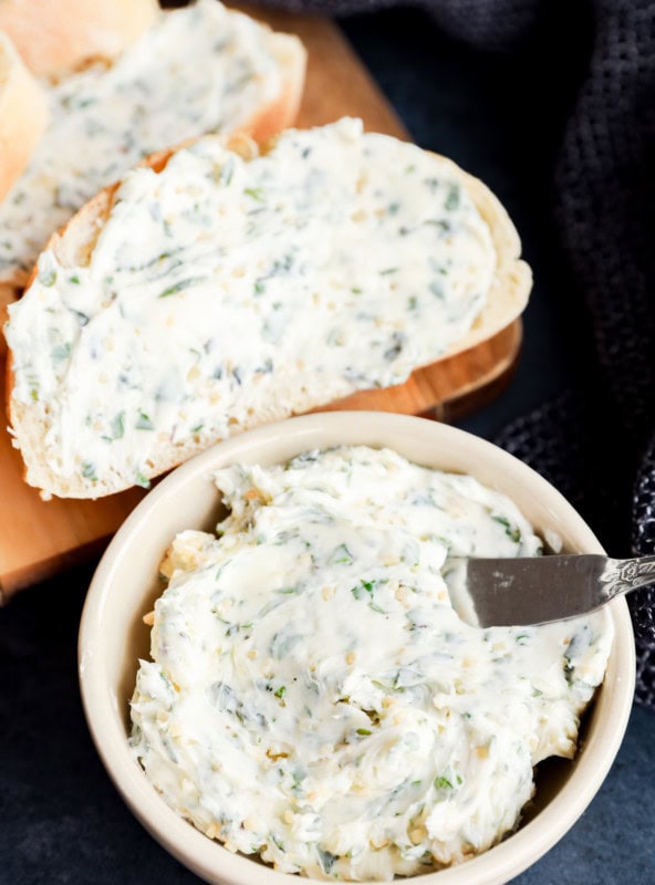 garlic herb butter in bowl and spread on bread on cutting board