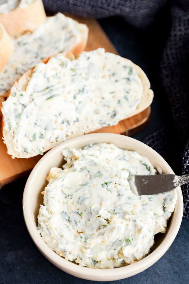 garlic herb butter in bowl and spread on bread on cutting board