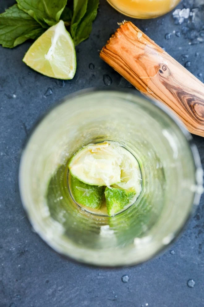 muddled lime in a shaker with muddler