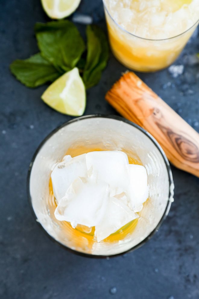 making an ipanema cocktail in a shaker with muddler on the side