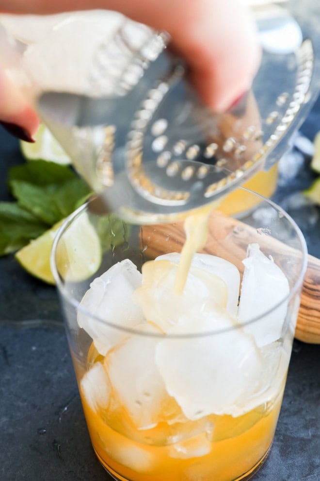 pouring ipanema cocktail into a glass through a strainer