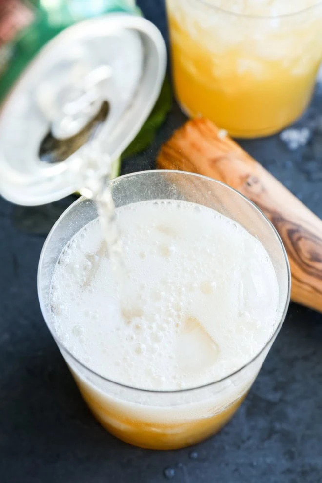 pouring ginger ale into a glass with ice