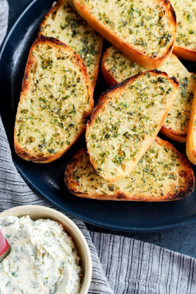 slices of sourdough garlic toast on a plate next to a bowl of butter