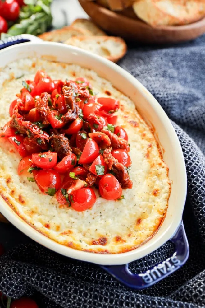 baked goat cheese appetizer in baking dish with tomato topping