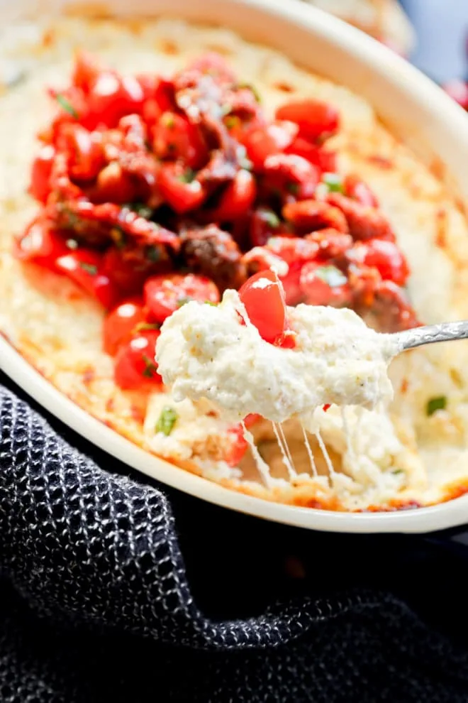 gooey cheese pull with spoon of baked goat cheese appetizer dip