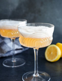 easy cocktail in coupe glasses with lemon halves