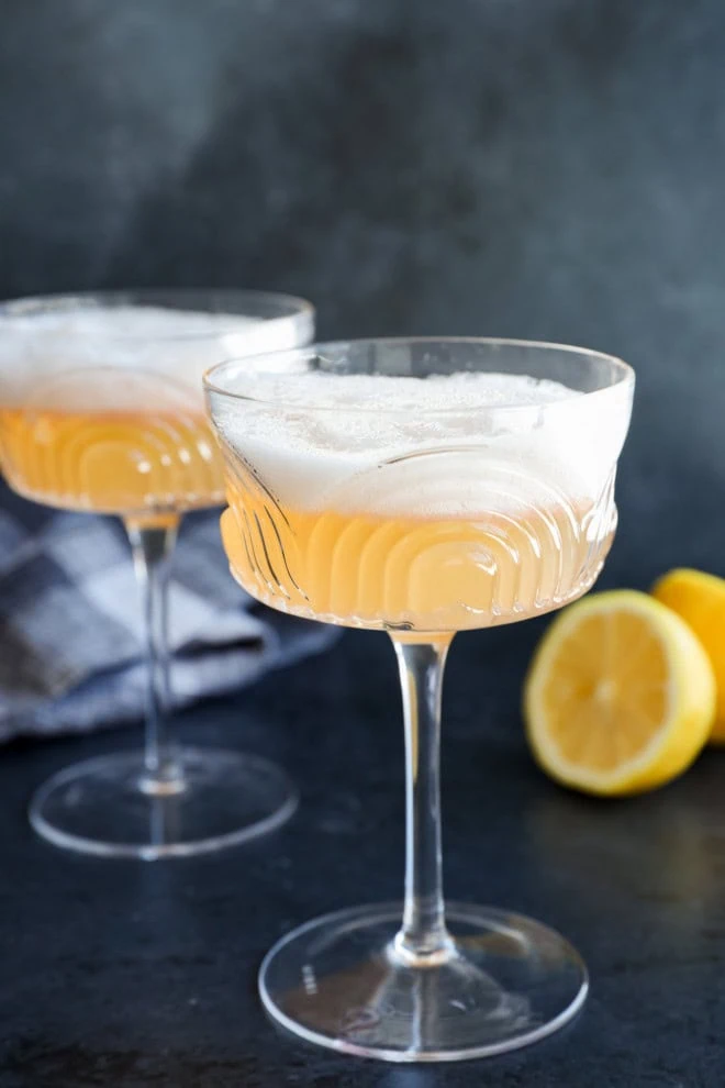 easy cocktail in coupe glasses with lemon halves