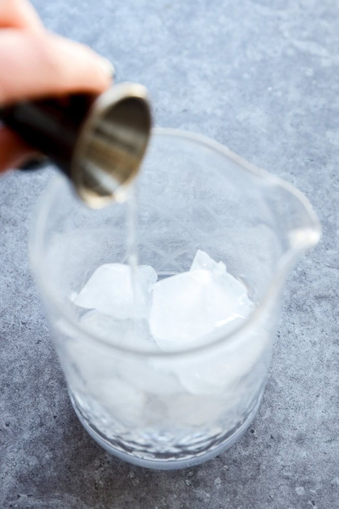 pour gin into a cocktail mixing glass with ice