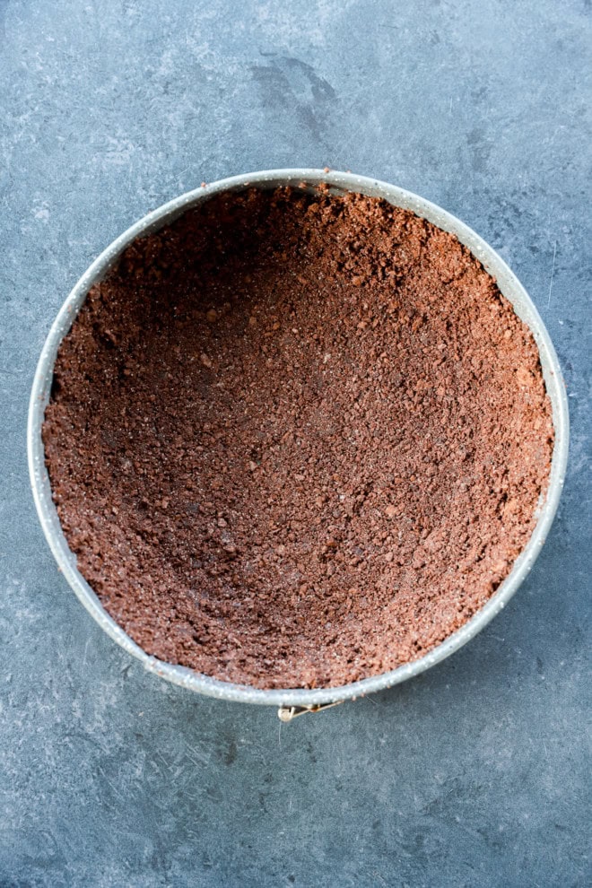 chocolate graham cracker crust in springform pan before baking