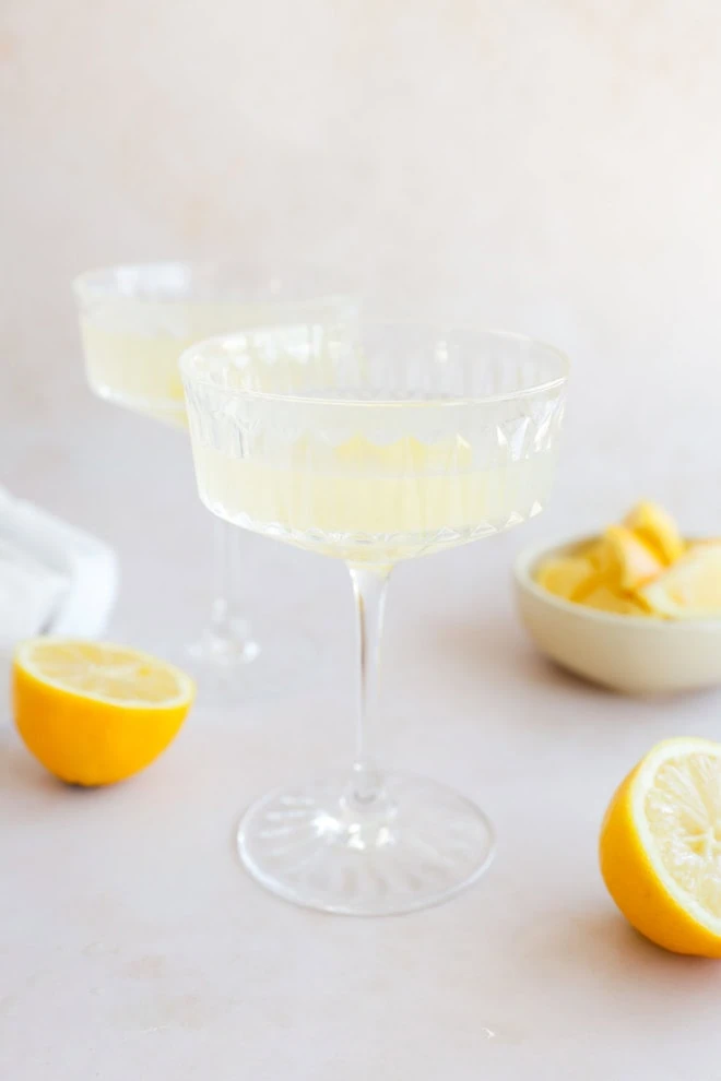 lemony cocktail with fresh lemons in cocktail coupe glasses