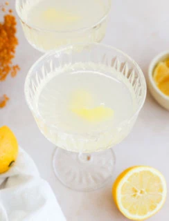 pretty bright lemon cocktail in couple glasses with lemon, white linen, and lemon wedges in a bowl