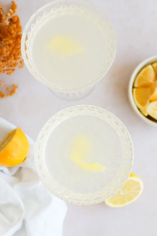 bees knees cocktails in coupe glasses with fresh lemons and flowers