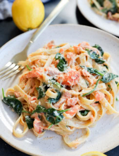 easy creamy fettuccine with seafood and greens on a plate with lemons and a fork